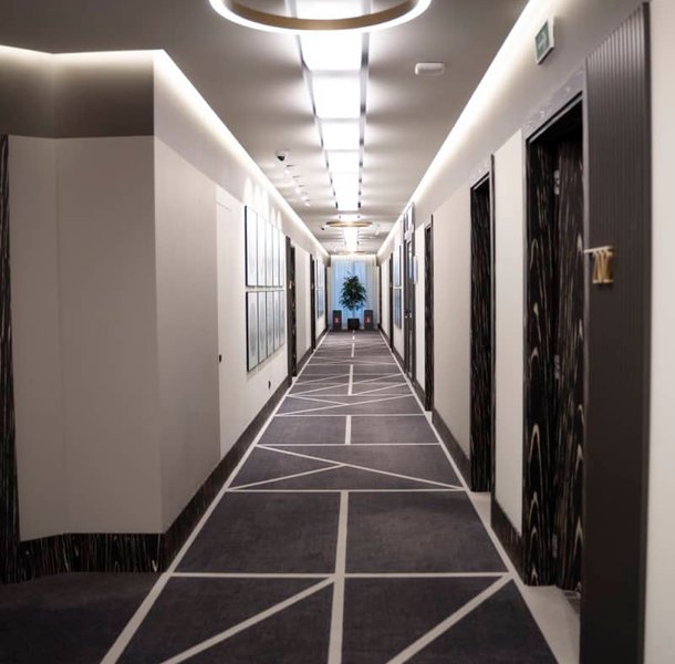 Hotel corridor with patterned carpet and recessed lighting.