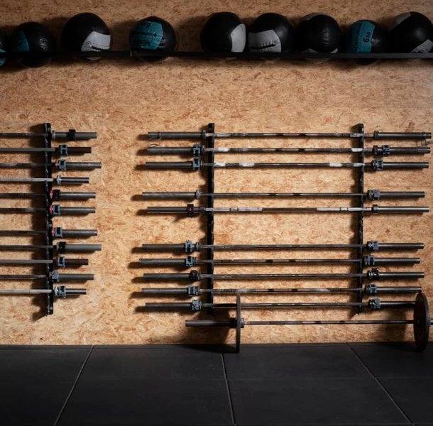 Gym equipment storage wall with racked barbells and weights.